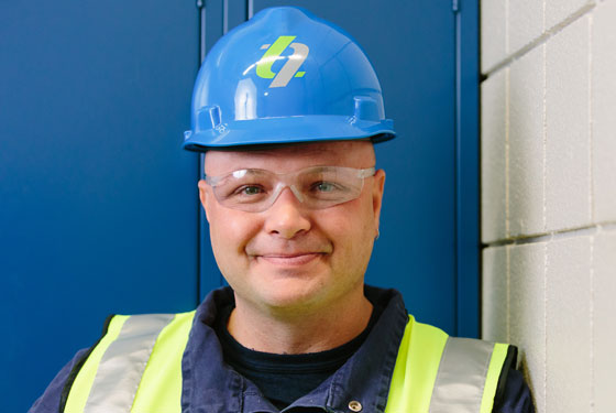 Picture of Tracey smiling and wearing a hardhat